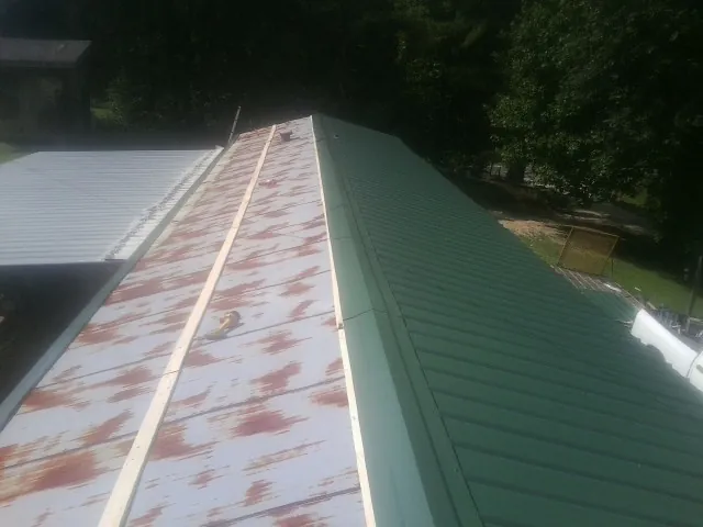 Old rusted panels beside newly installed green metal roofing — Wind Damage Roof Repair by Roofing Brothers in Low Moor