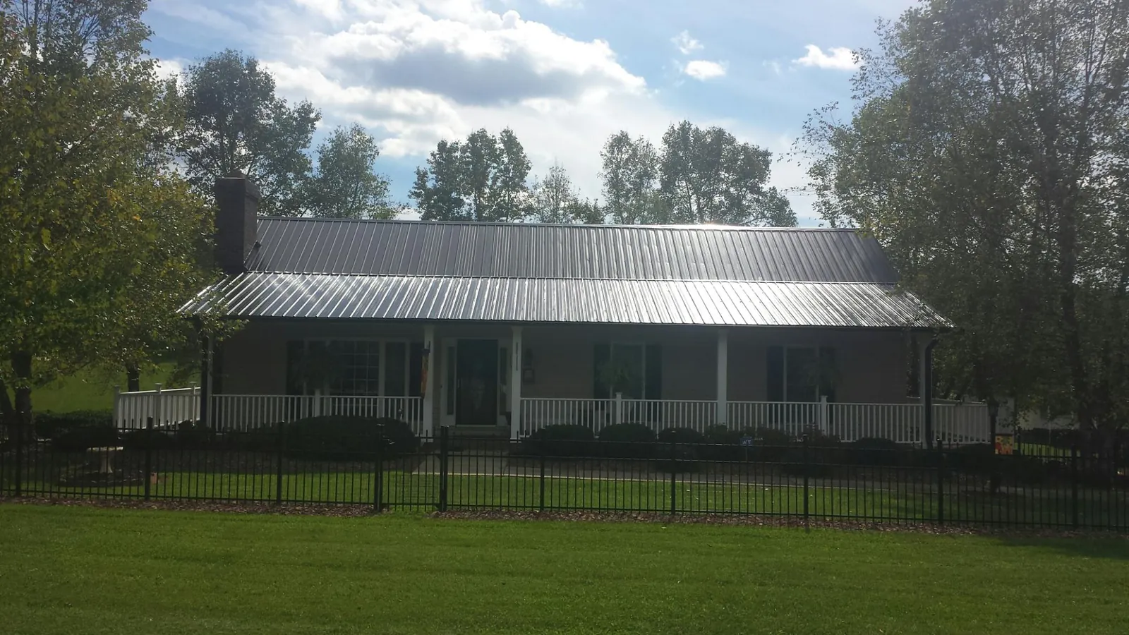 Gray metal roof on a brick ranch with a full width front porch — Gutter Guard Installation work by our crew in Low Moor
