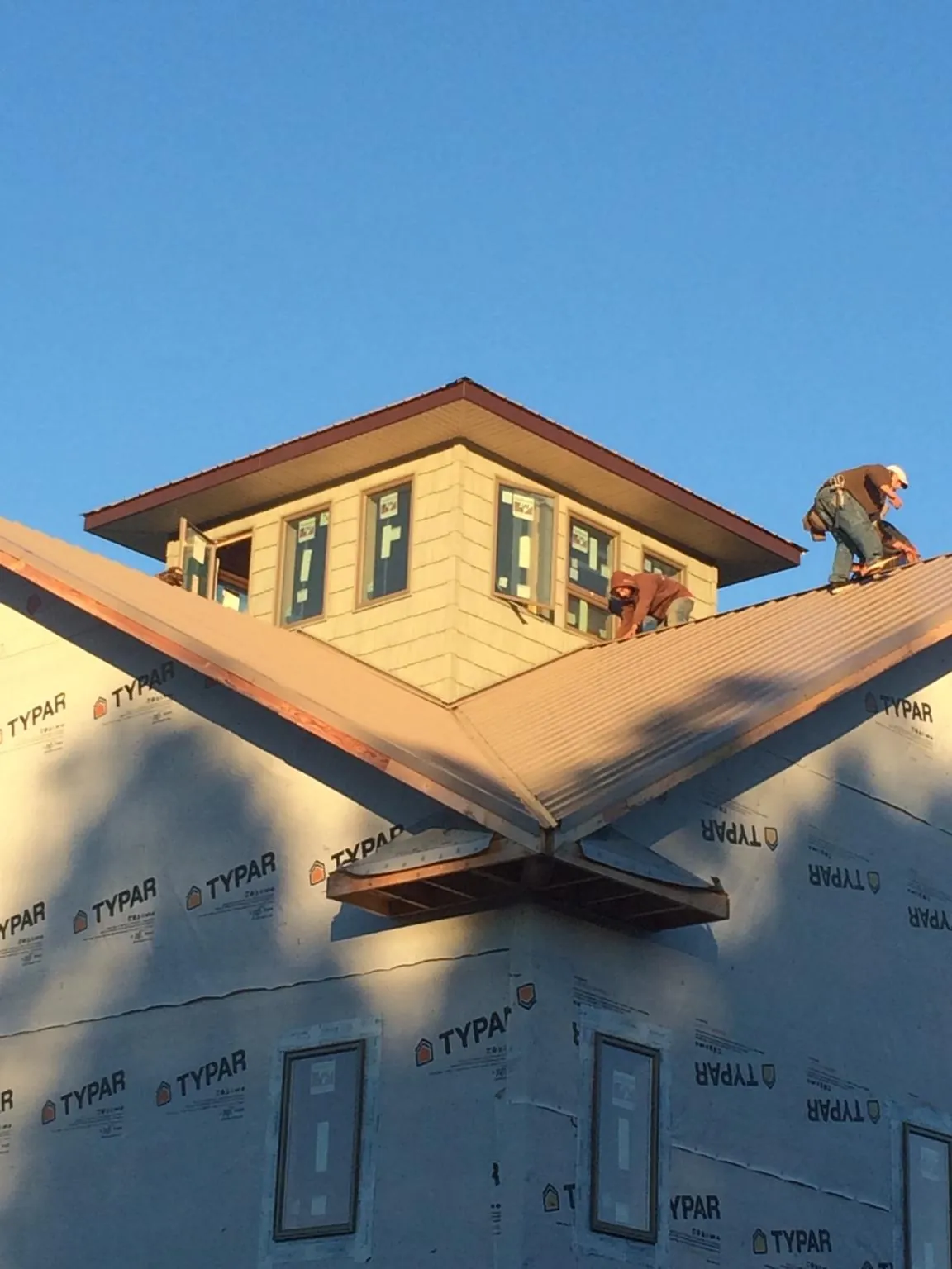 Roofers working around a rooftop cupola on a new metal roof at sunset — Roof Waterproofing in Low Moor by Roofing Brothers